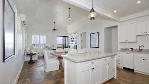 A spacious kitchen with white cabinetry, a large island, and pendant lighting. - Coastal Chic: New Luxury Oceanfront Home With Sunset Views (Governor's Harbour)