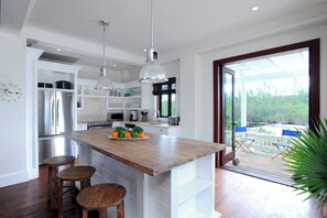 Una cocina moderna con una isla de madera, electrodomésticos de acero inoxidable y un amplio ventanal con vistas a una terraza.