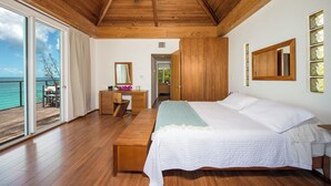 Une chambre avec un plafond en bois, un lit, une commode et une vue sur l’océan.
