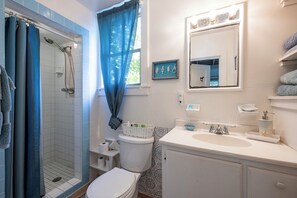 A bathroom with a shower, toilet, sink, and a mirror.