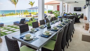A covered dining area with a view of the ocean, outdoor seating, and a pool. - Island Haven: Oceanfront Retreat With Infinity Pool (Blowing Point)