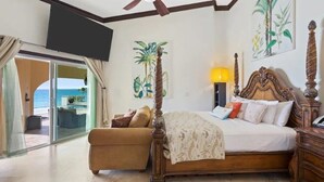 A bedroom with a bed, a sofa, a TV, and a view of the ocean. - Beachfront Bliss: Private Retreat With Spectacular Views (Blowing Point)