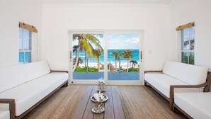 Une chambre avec vue sur la plage, comprenant deux canapés blancs et une petite table ornée de bougies.