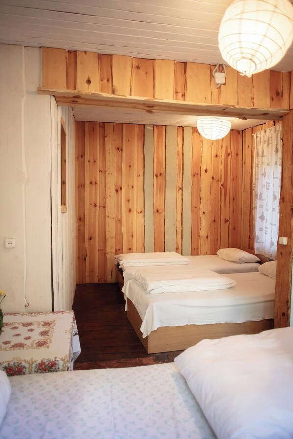 Una habitación con paneles de madera, una cama con ropa de cama blanca y una lámpara colgante.