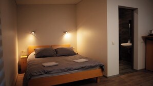 A bedroom with a wooden bed, two bedside lamps, and a nightstand. - Asmonai Campsite (Kintai)