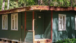 A green wooden cabin with a porch, a door, and windows. - Asmonai Campsite (Kintai)
