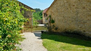 Un bâtiment en pierre avec un chemin de gravier menant à une porte en bois.