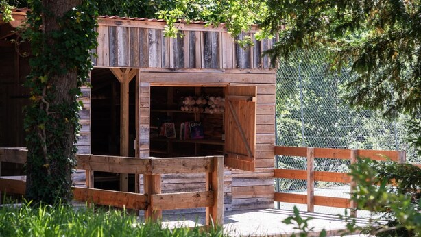 Une cabane rustique en bois, dotée d’une porte en bois et d’un petit espace porche.