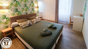 Ein ordentlich eingerichtetes Schlafzimmer mit einem Bett, Nachttischen, einem Schreibtisch und einem Stuhl.