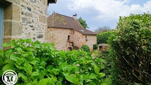 Un edificio in pietra con tetto in tegole, immerso nel verde.