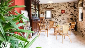 Una stanza rustica con pareti in pietra, un armadietto in legno, mobili in vimini e una pianta in vaso.
