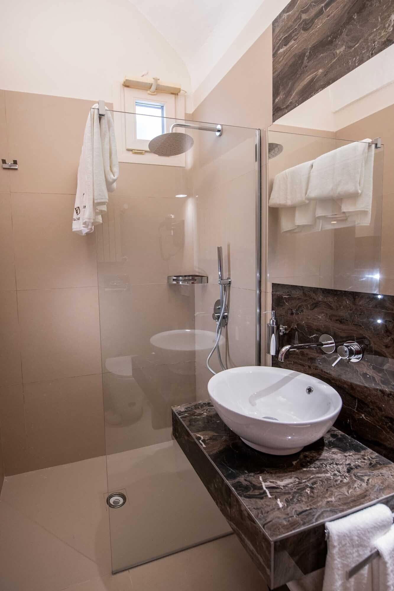 A modern bathroom with a glass-enclosed shower, a white sink, and a marble countertop.