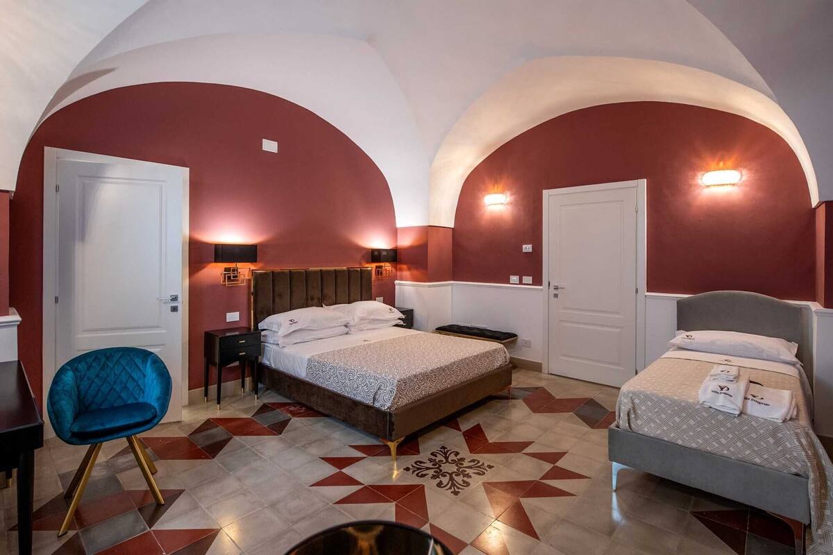 Ein Hotelzimmer mit zwei Betten, einem blauen Sessel und einem dekorativen Fußboden mit Sternenmuster.