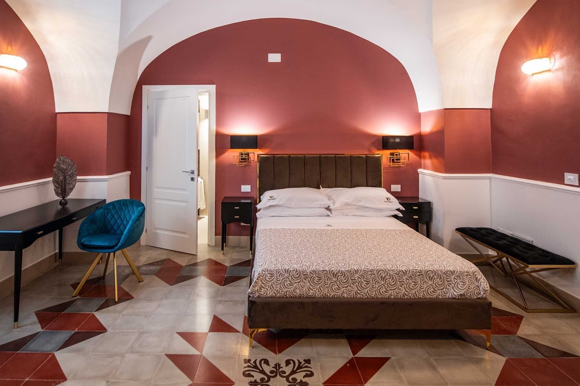 Una habitación de hotel con cama, escritorio, silla y banca.