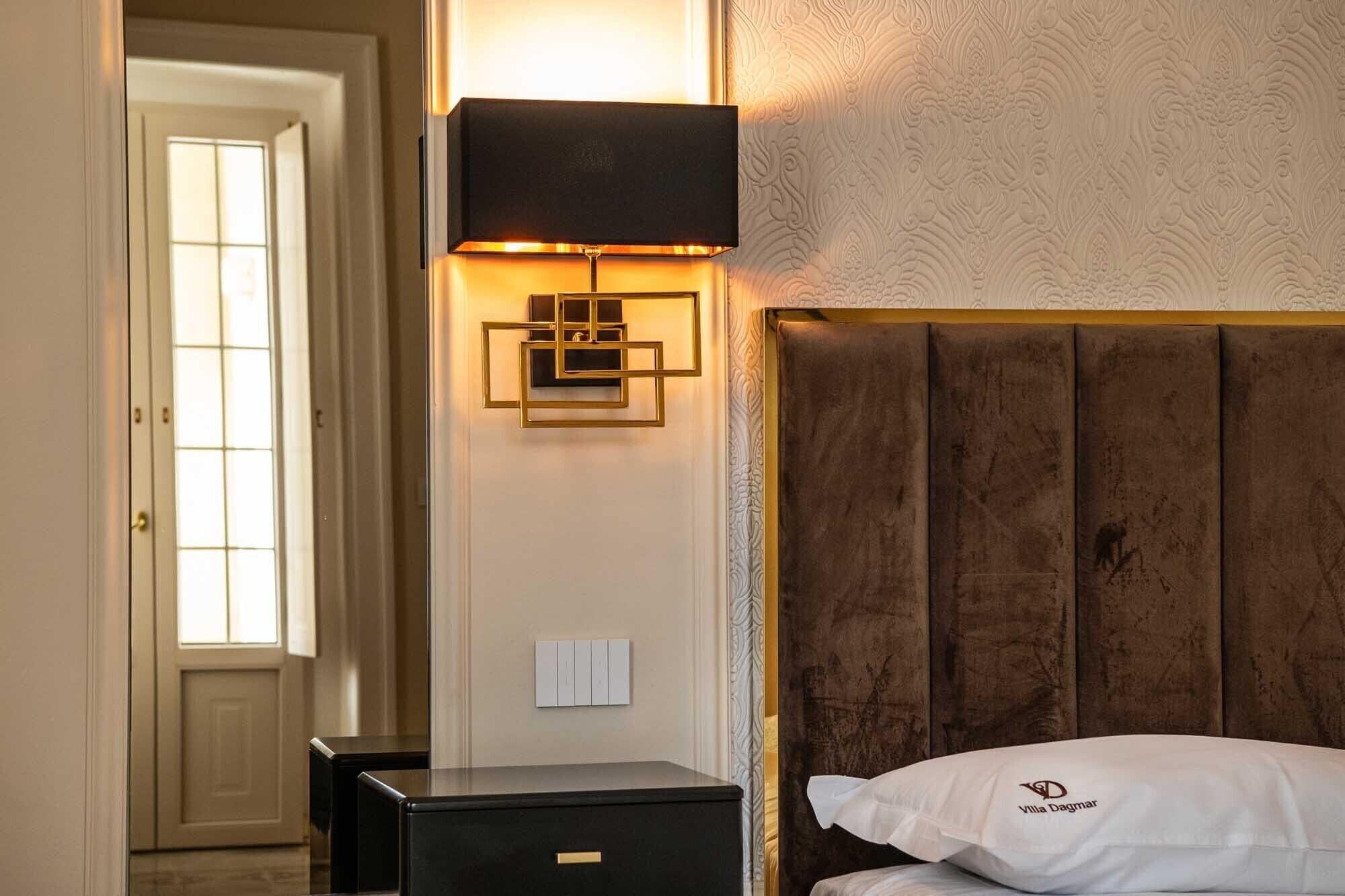 Une chambre d’hôtel avec une tête de lit en bois, une table de chevet et un luminaire fixé au mur.