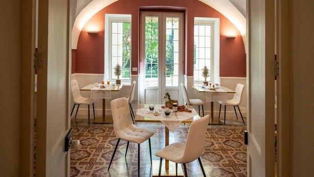 Un comedor con un techo alto en arco, dos ventanas con marcos blancos y un suelo estampado.