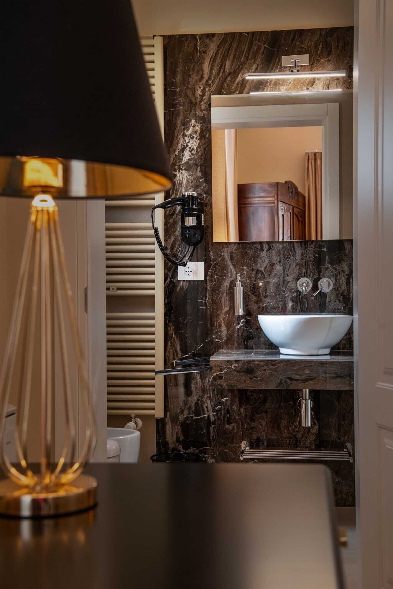 Une salle de bain avec un lavabo en marbre, un miroir et une lampe noire.