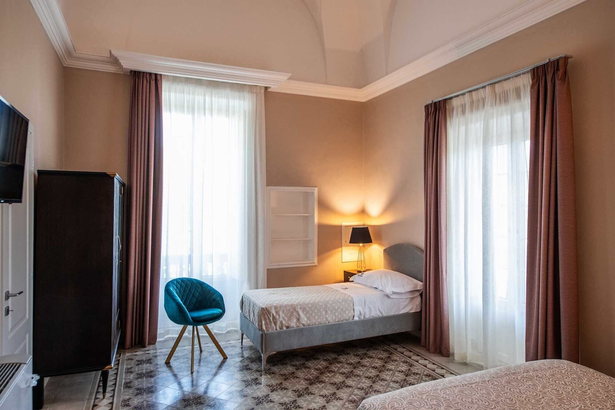 A hotel room with a bed, a chair, a desk, and a television.