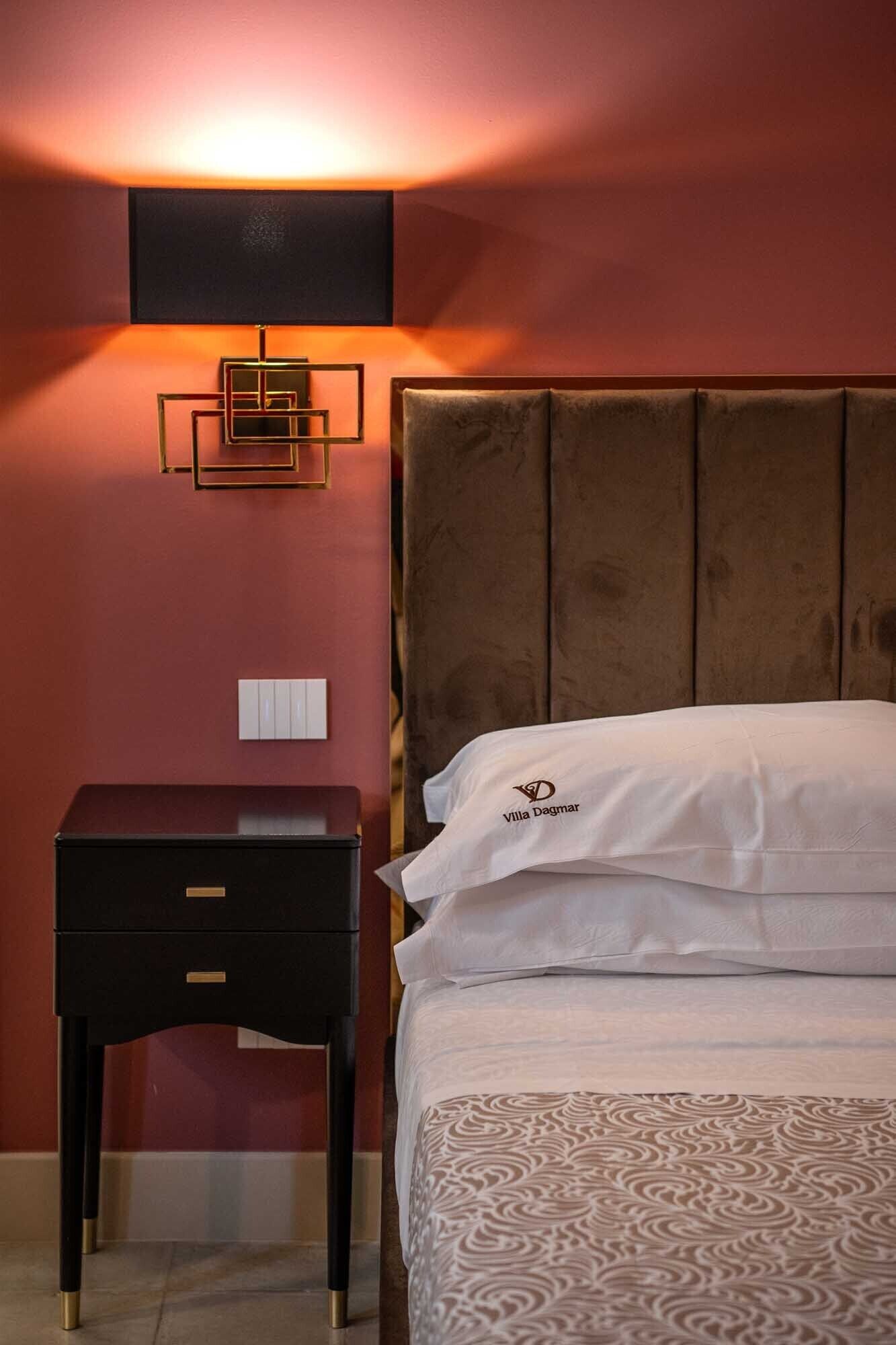 Une chambre d’hôtel équipée d’un lit, d’une table de chevet, d’une lampe fixée au mur et d’une prise électrique.