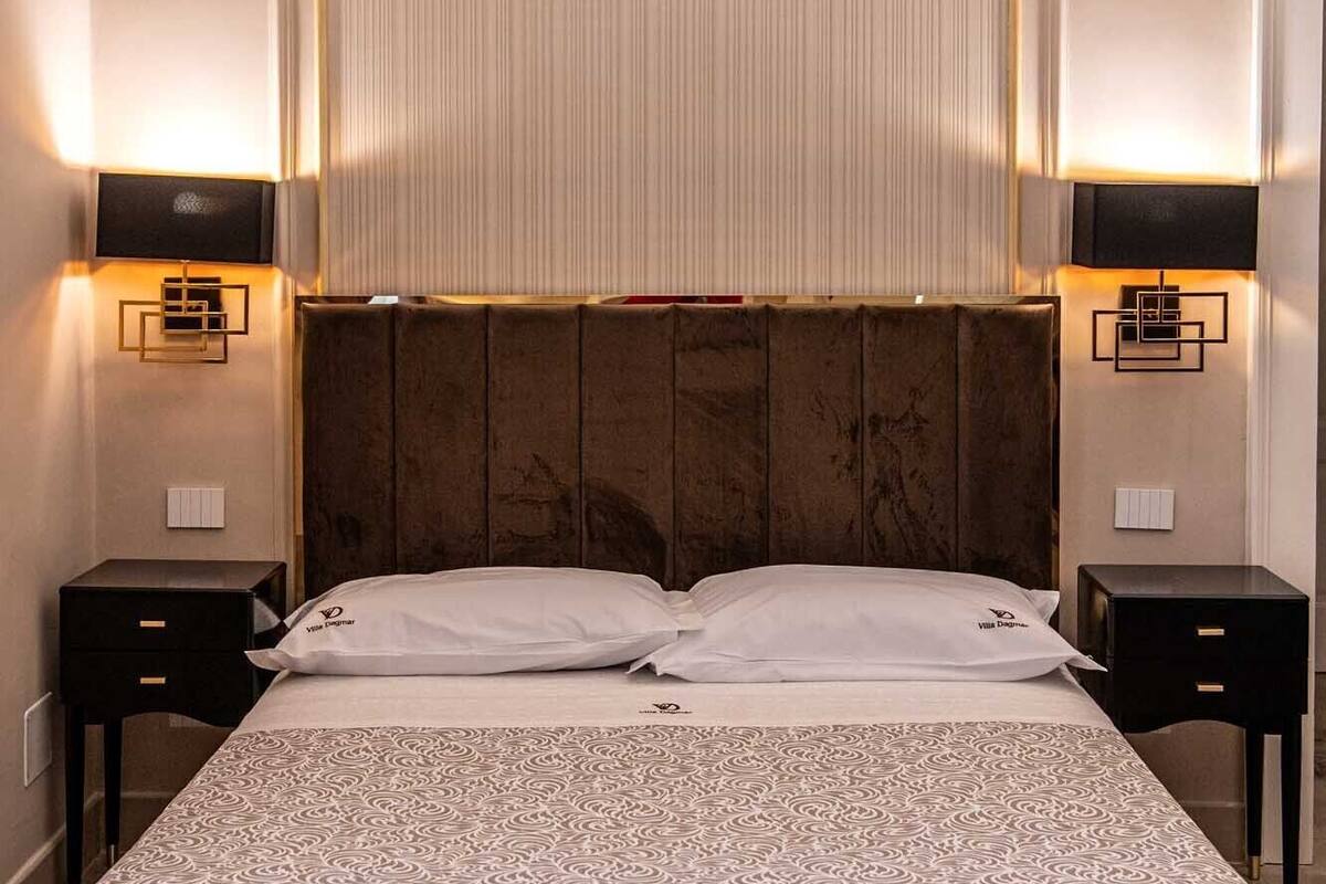 Ein Hotelzimmer mit einem großen Bett, zwei Nachttischen und einem Kopfteil mit vertikalen Linien.