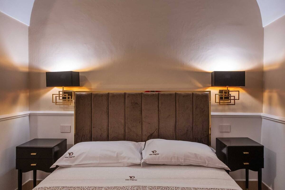 Ein Hotelzimmer mit einem großen Bett, zwei Nachttischen, einer Kopfteil und Wandleuchten.