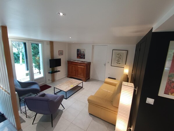 Una sala de estar con un sofá, sillas, un televisor, un mueble y una ventana.