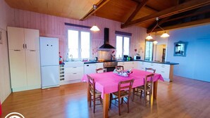Una cocina amplia con armarios de madera, una mesa de comedor con mantel rosa y un ventanal que proporciona luz natural.