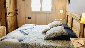 Una habitación con una cama, paredes de madera, un ventanal y una lámpara.