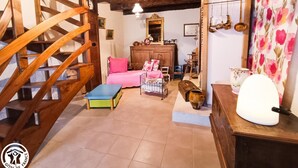Ein rustikaler Raum mit einer Holztreppe, einem Bett mit rosa Bettwäsche, einem Holzschrank und einem blumigen Vorhang.
