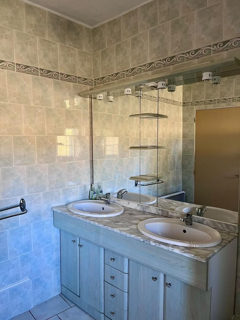 Un baño con dos lavamanos, un espejo y un perchero para toallas.