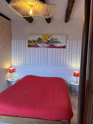 A room with a bed, two bedside lamps, a wall-mounted artwork, and a unique ceiling light fixture.