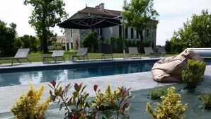 Un área de piscina con sillones de descanso y una zona de estar cubierta.