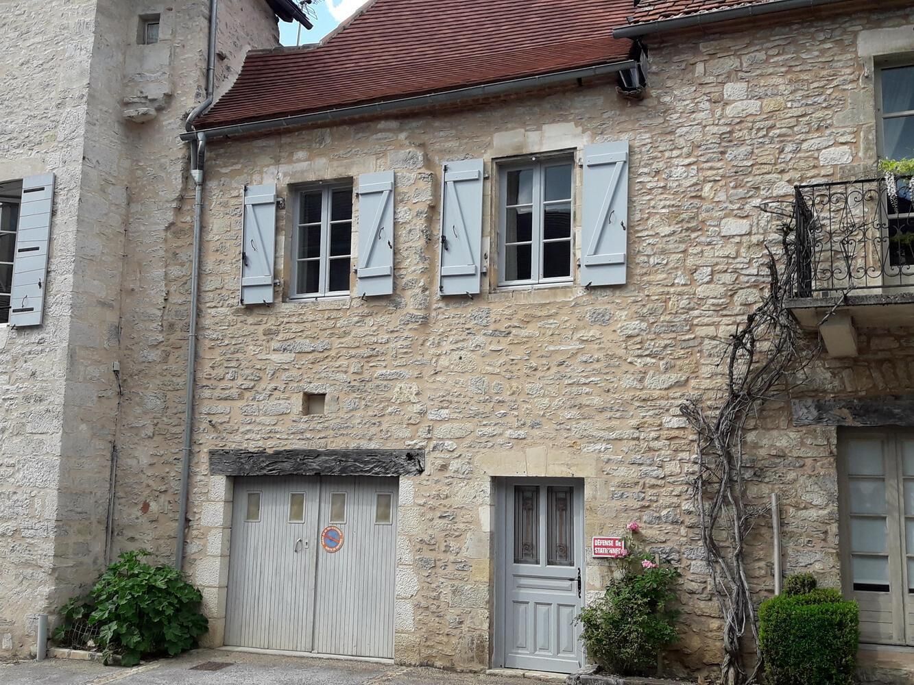 Un bâtiment en pierre doté de nombreuses fenêtres et portes, dont certaines sont équipées de volets.