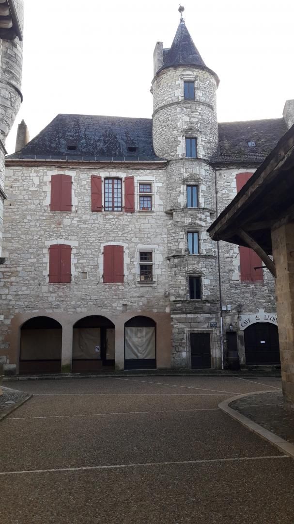 Un bâtiment historique en pierre, doté d’une tour centrale, de fenêtres en arc et d’une entrée couverte.