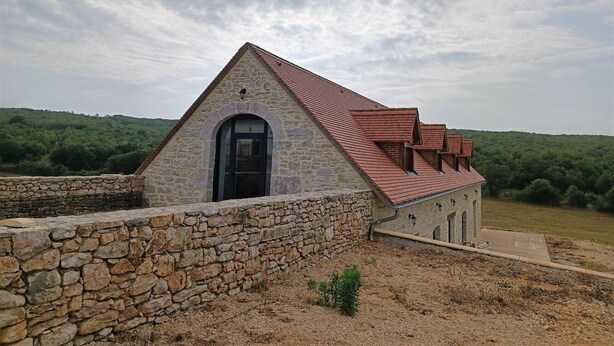 Un edificio de piedra con techo de tejas rojas, una pared de piedra y una puerta.