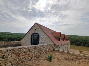 Un bâtiment en pierre avec un toit recouvert de tuiles rouges, un mur en pierre et une porte.