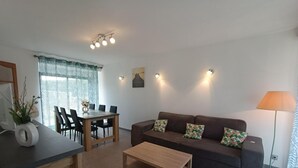 Una sala moderna con sofá, mesa de centro, mesa de comedor y sillas.