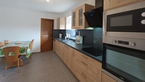 Una cocina moderna con armarios de madera, encimera negra y electrodomésticos de acero inoxidable, incluyendo un microondas y un horno.
