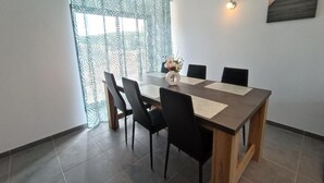 Un comedor con mesa de madera, sillas negras, un jarrón con flores y un cuadro en la pared.