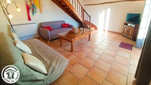 Uma sala de estar com sofá, mesa de centro, televisão e escada.