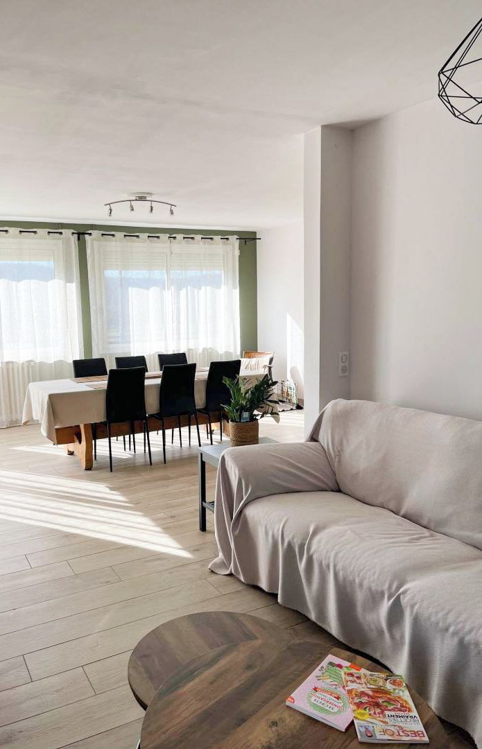 A modern living room with a sofa, a dining table with chairs, and a coffee table.