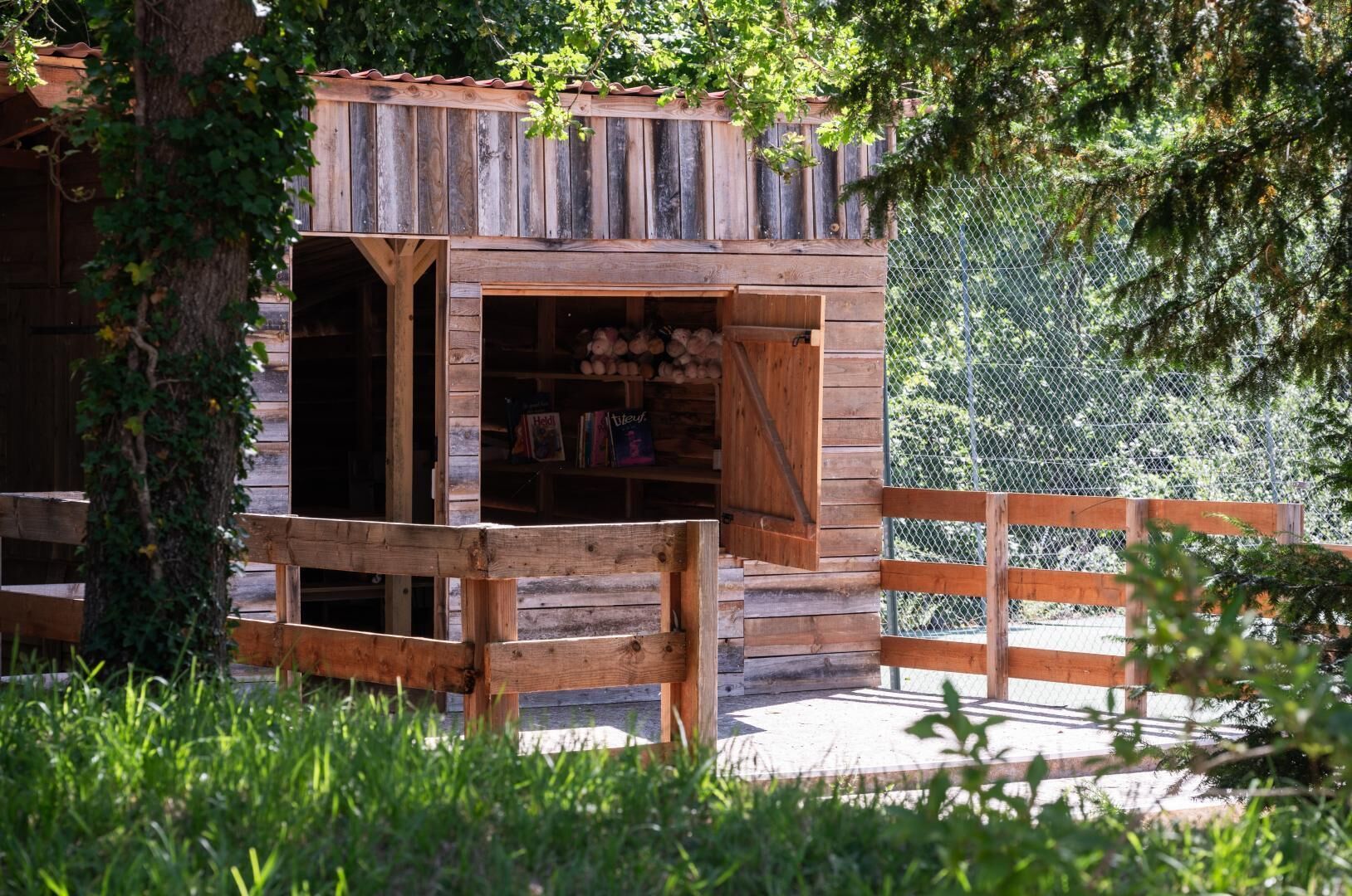 Une cabane rustique en bois, dotée d’une porte en bois et d’un petit espace porche.