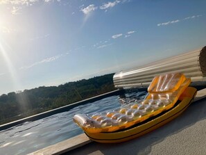 Una silla hinchable de descanso junto a una piscina en azotea, con una vista despejada del paisaje circundante.