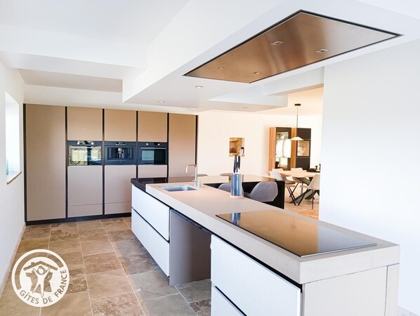 Una cocina moderna con electrodomésticos integrados, una isla central y un comedor con vistas.