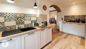 A modern kitchen with patterned tiles, a sink, cabinets, and a coffee machine.