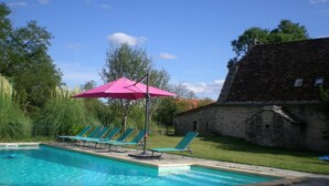 A swimming pool with lounge chairs and a pink umbrella.