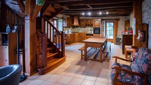 A rustic kitchen with wooden cabinets, a dining table, and a staircase.