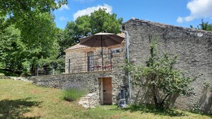 A stone building with a balcony and outdoor seating area. - Gîtes de France® - La Bouyssounade (CRAYSSAC)