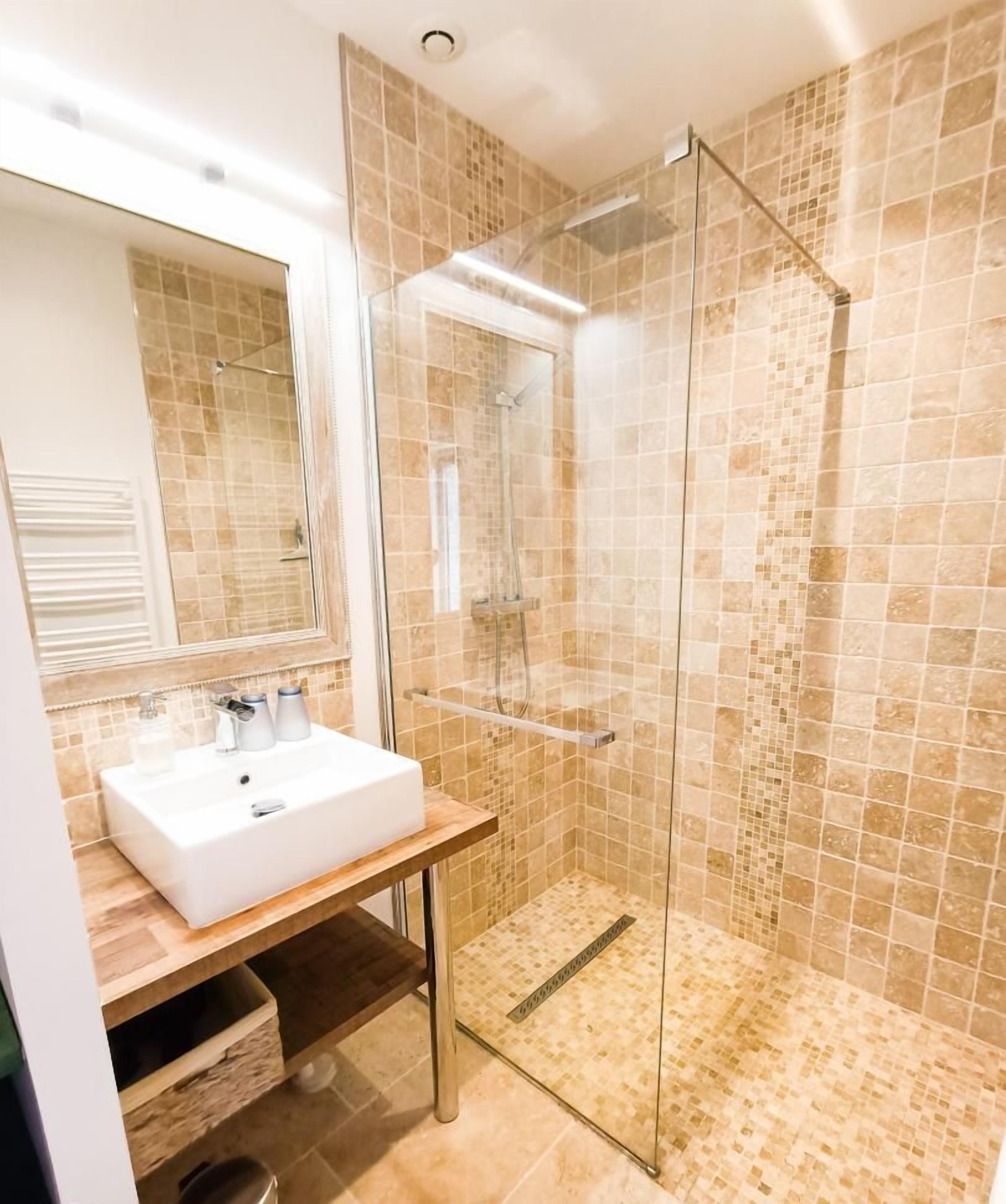 A bathroom with a glass-enclosed shower, a white sink, and a mirror.