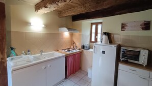 Uma cozinha compacta com armários brancos, fogão a gás, geladeira, torradeira e janela com vista.